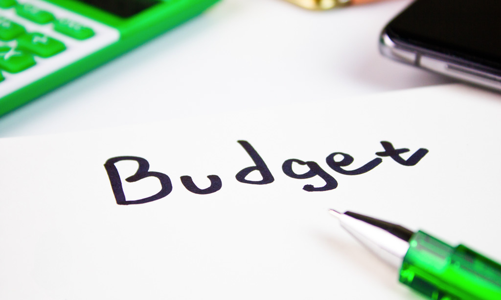 The word Budget hand written on paper with a calculator on the desk