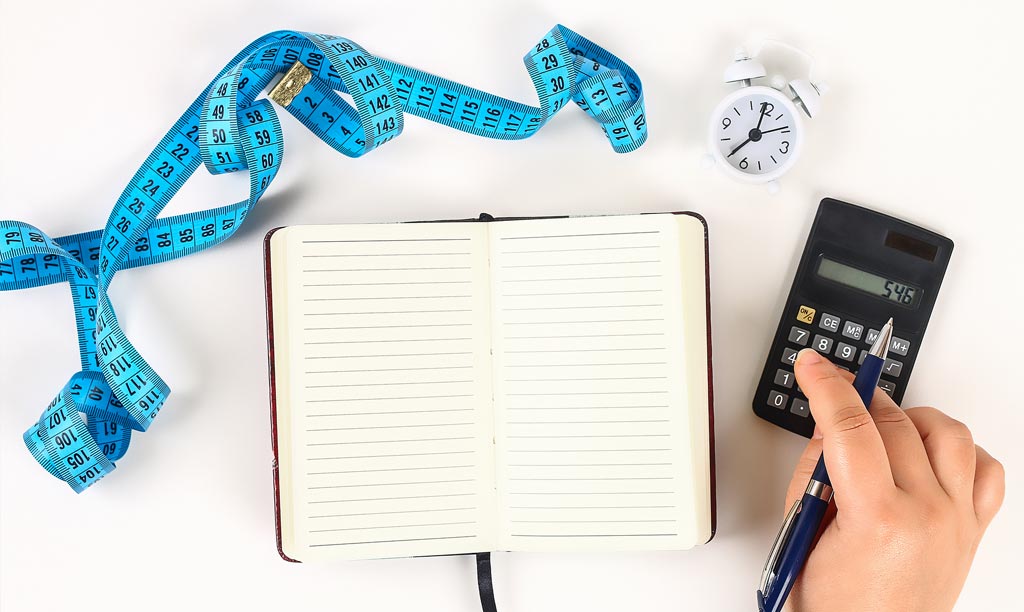 A desktop with a pad, calculator and tape measure